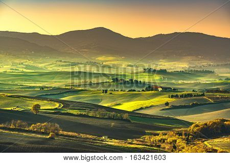 Tuscany countryside misty panorama rolling hills and green fields on sunset. Pisa Italy Europe