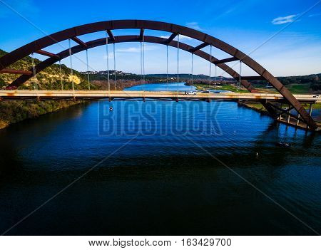 deep blue austin landsape amazing austin view at Pennybacker Bridge aerial view straight down above modern architecture spanning colorado river 360 bridge with boat going by Texas Hill country with traffic and cars driving transportation aerial drone view