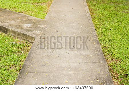 Junction of walking path or walkway or walkpath in garden with green grass.