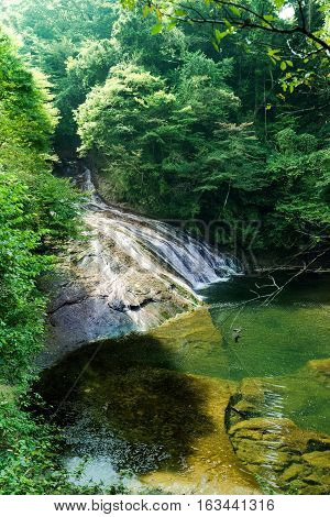 Japan travel concept - beautiful yoro keikoku valley waterfall under dramatic sun glow and morning blue sky in Chiba Prefecture Japan