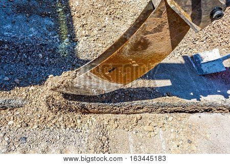 Mini excavator with narrow bucket for laying fiber-optic cable line. Detail bucket narrow