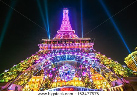 Macau, China - December 8, 2016: Perspective view of colorful Macau Eiffel Tower, icon of The Parisian, a luxury Resort Hotel Casino in Cotai Strip while shines bright at night during the laser show.
