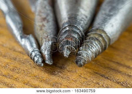 Several different sizes old gimlets, hand-tools for drilling holes in wood. Macro Brown plywood background