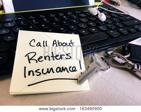 Note on mobile tablet keyboard "find out about renters insurance" to-do list reminder next to new apartment keys on home desk