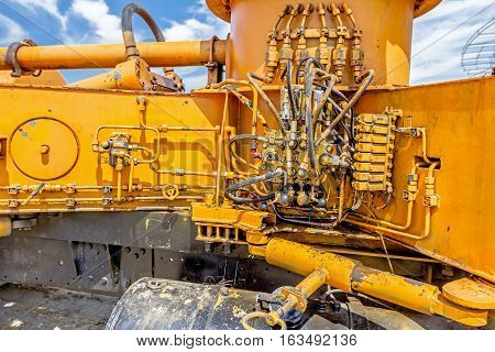 Hydraulic pressure pipes and connection fittings levers valves on control panel of industrial system on construction machinery.