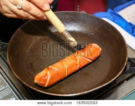Grilling sausage raw meat on a pan