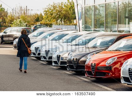 PARIS FRANCE - OCT 10 2015: Woman walking between rows of new car to choose the most precious one at the Alfa Romeo car store