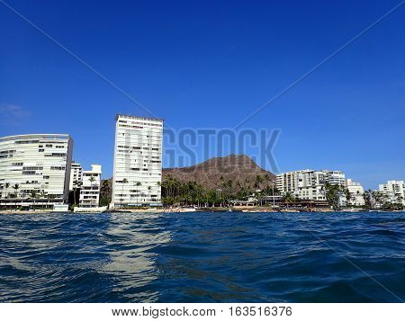 Wavy water on ocean off Kaimana Beach with Diamondhead hotels and condos on Oahu Hawaii.