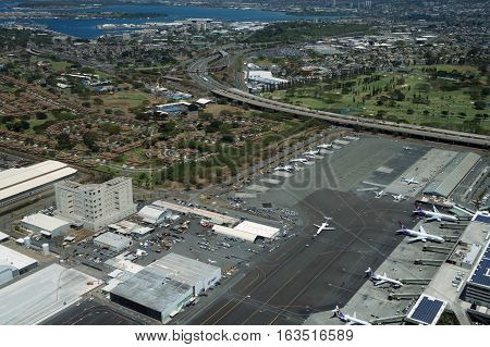 HONOLULU - APRIL 20: Aerial view of planes helicopters Golf Course Pearl Harbor Parking lots Roads leading into Airport and cars parked by buildings at the Honolulu International Airport HNL next to the water on Oahu Hawaii. April 20 2016.