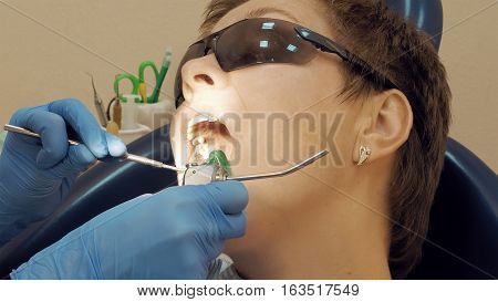 Woman at the dentist clinic office gets dental medical examination and treatment. Close up shot. Odontic and mouth health is important part of modern human life that dentistry help with.