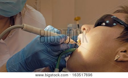 Woman at the dental hygienist and dentist clinic professional tooth whitening and ultrasound cleaning. Odontic and mouth health and hygiene is important part of human life that dentistry help with.