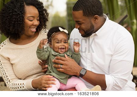 African American Family playing and laughing with their daughter.