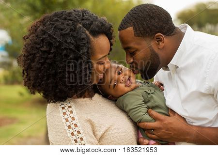 African American Family playing and laughing with their daughter.