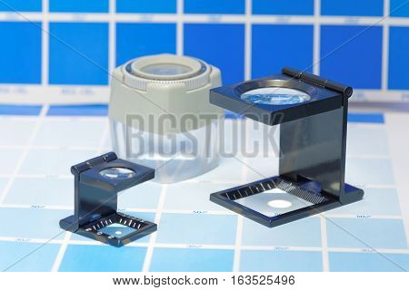 Three magnifier or printer's loupe sits on a cyan test sheet in a pre-press workshop