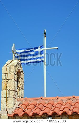 Greek flag and church bell tower against a blue sky in the harbour Kalyves Crete Greece Europe.