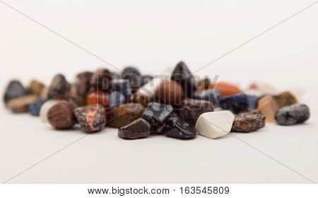 Scattering of colorful smooth stones. White background. Collection of stones. Round precious and semi-precious minerals. Polished minerals. Beautiful natural stones.