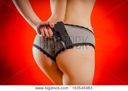 sexy woman in lingerie holding a gun at the buttocks