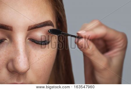 Master makeup corrects and gives shape to pull out with forceps previously painted with henna eyebrows in a beauty salon. Professional care for face.