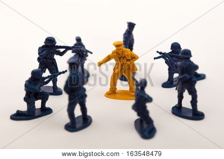 Blue toy soldiers surrounding a brown toy soldier