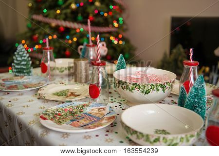 Christmas and New Year table place setting with empty Christmas plates with festive decorations bauble snowflake star bow ball pinecone berry candy cane. Christmas Xmas New Year holiday dinner background.