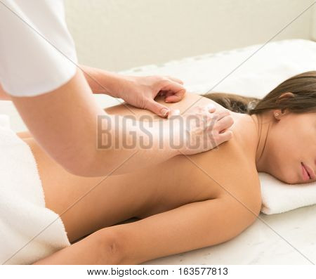 Caucasian woman getting medical massage in spa. She is very relaxed