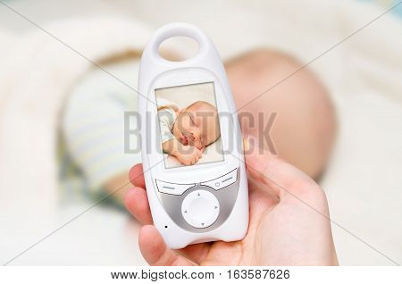 Hand holding video baby monitor for security of the baby