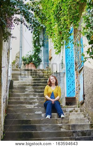 Tourist sitting on stairs in Positano beautiful Mediterranean village on Amalfi Coast (Costiera Amalfitana) in Campania Italy