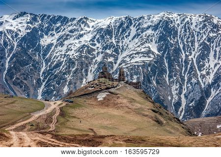 Georgia . Stepantsminda village . Gergeti Sameba Orthodox church on a background of mountain spring .