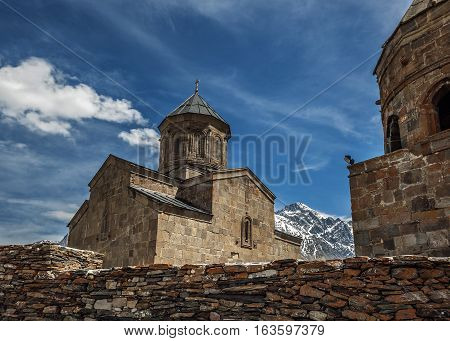 Georgia . Stepantsminda village . Gergeti Sameba Orthodox church on a background of mountain spring .