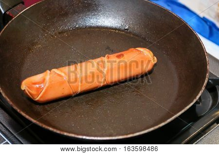 Grilling sausage raw meat on a pan