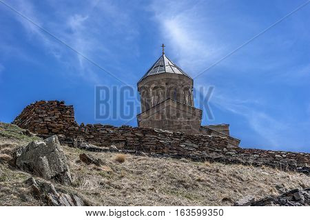 Georgia . Stepantsminda village . Gergeti Sameba Orthodox church on a background of mountain spring .