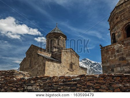 Georgia . Stepantsminda village . Gergeti Sameba Orthodox church on a background of mountain spring .