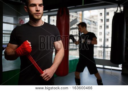 Sportsman engaged boxing in black shirt in gym