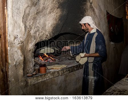 NAZARETH ISRAEL - DECEMBER 16: Man dressed in period clothes bakes bread in Nazareth Village Israel on December 16 2016