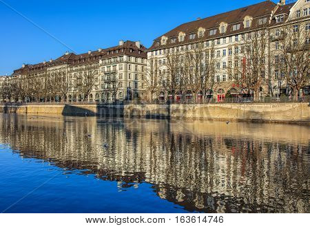 Zurich, Switzerland - 1 January, 2017: the Limmat river, trees and buildings along it in wintertime. The Limmat is a river, which commences at the outfall of Lake Zurich in the southern part of the city of Zurich and flows in northwesterly direction.
