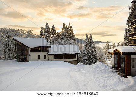 Myoko ski lodges during early morning sunrise.  Low cloud cover hovers over the lower parts of town. There are no people to be seen at this time of day.