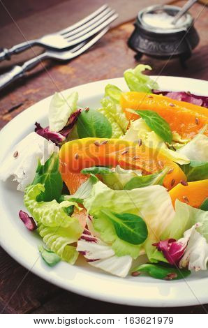 Fall salad with greens, arugula, flax seeds and roasted squash, pumpkin on wooden background, rustic style, toned, vertical