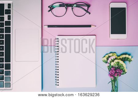 Flat lay, top view office table desk. feminine desk workspace with succulent, laptop, glasses, diary on pink and blue background.