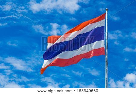 Thailand national flag on the flag pole wind blown against blue sky background