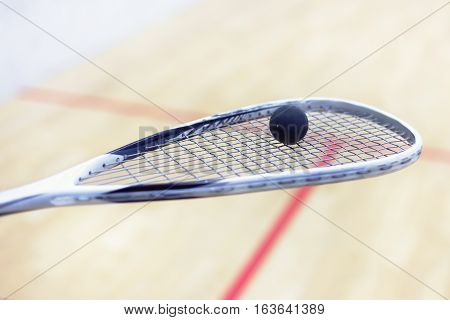 squash racket and ball. Racquetball equipment. Squash ball on squash racket with court on the background. Photo with toning and selective focus