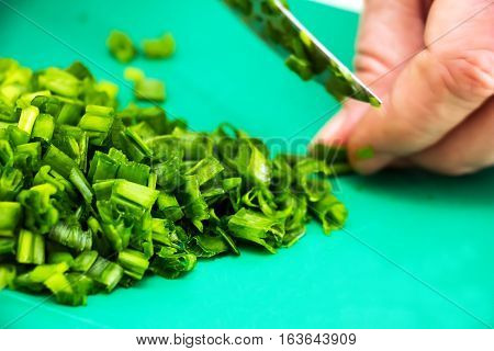 Woman chopping green onion with knife on the table in the kitchen. Healthy eating, cooking, vegetarian food. 2