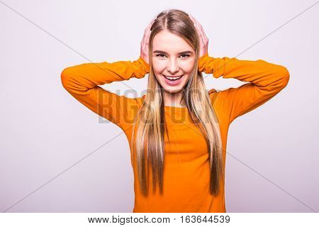 Happy Blonde Girl In Orange T-shirt Close Ears With Hands On White