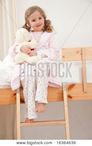 Roztomilá dívka v pyjama objímání no-name medvídek