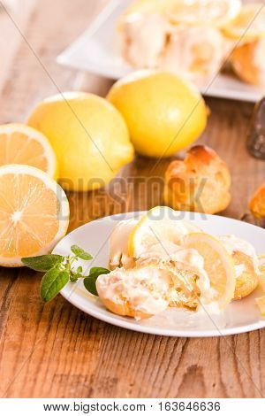 Lemon Profiteroles with custurd cream on white dish.