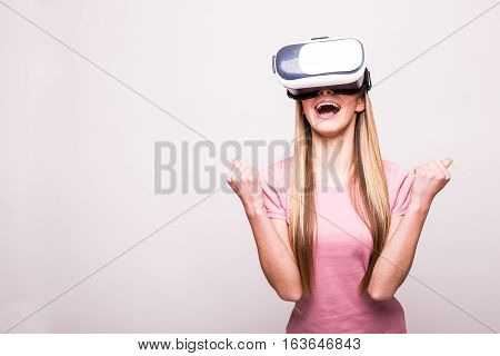 Happy woman wearing virtual reality goggles on grey