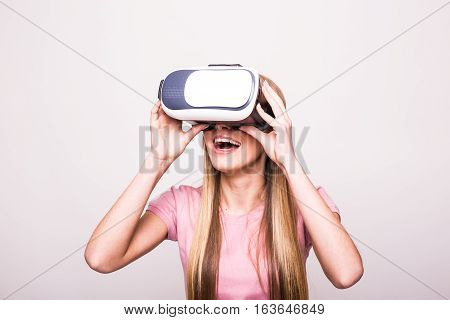 Joyful young girl using a VR headset and smiling isolated on white background
