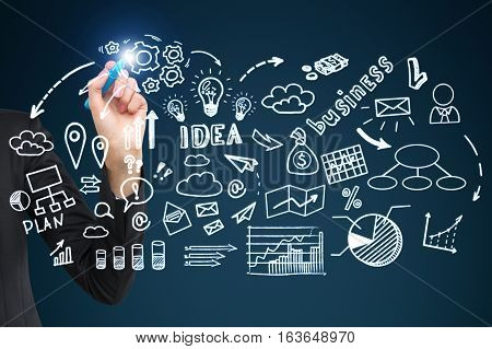 Close up of a businessman's hand with a glowing pen drawing a business idea sketch on a glassboard. Concept of development and business education