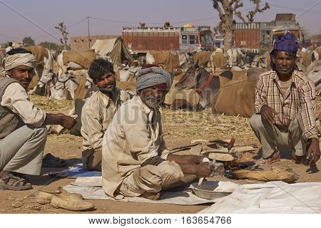NAGAUR, RAJASTHAN, INDIA - FEBRUARY 15, 2008: Group of men prepare the first meal of the day after a night in the open at the annual livestock fair in Nagaur, India.