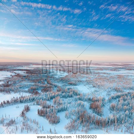 Aerial view above the endless snow covered tundra river in time of short winter day.