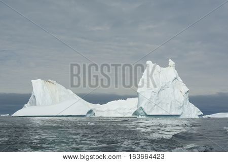 ancipitate iceberg in Antarctic waters on a cloudy day